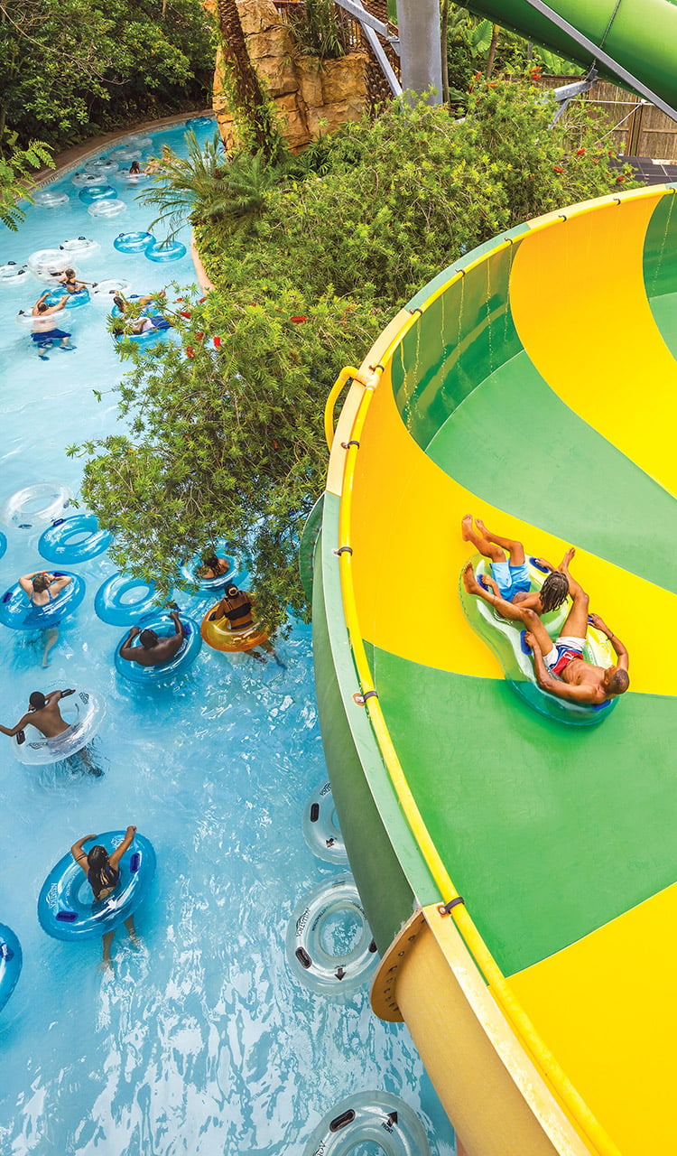 A view of a lazy river and a waterslide funnel with people floating in inner tubes
