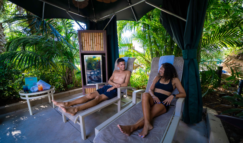 Two people in lounge chairs in a cabana